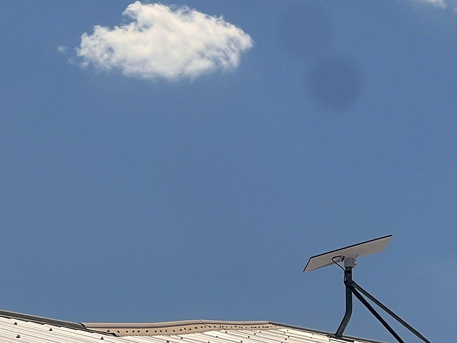 Starlink dish mounted beside a TV antenna on a house roof at Pike River